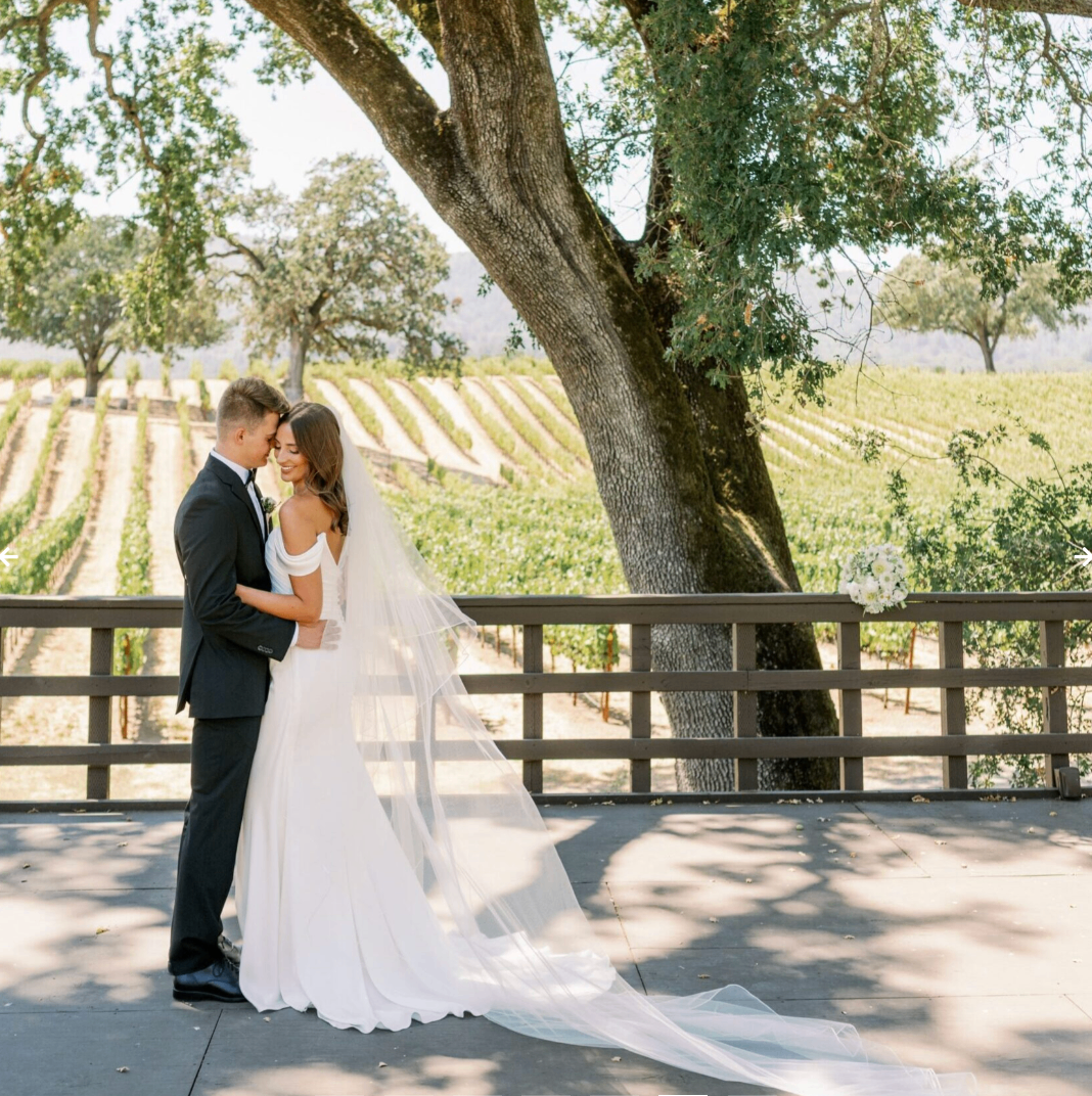 Couple embracing on the amphitheater stage beneath a heritage oak tree